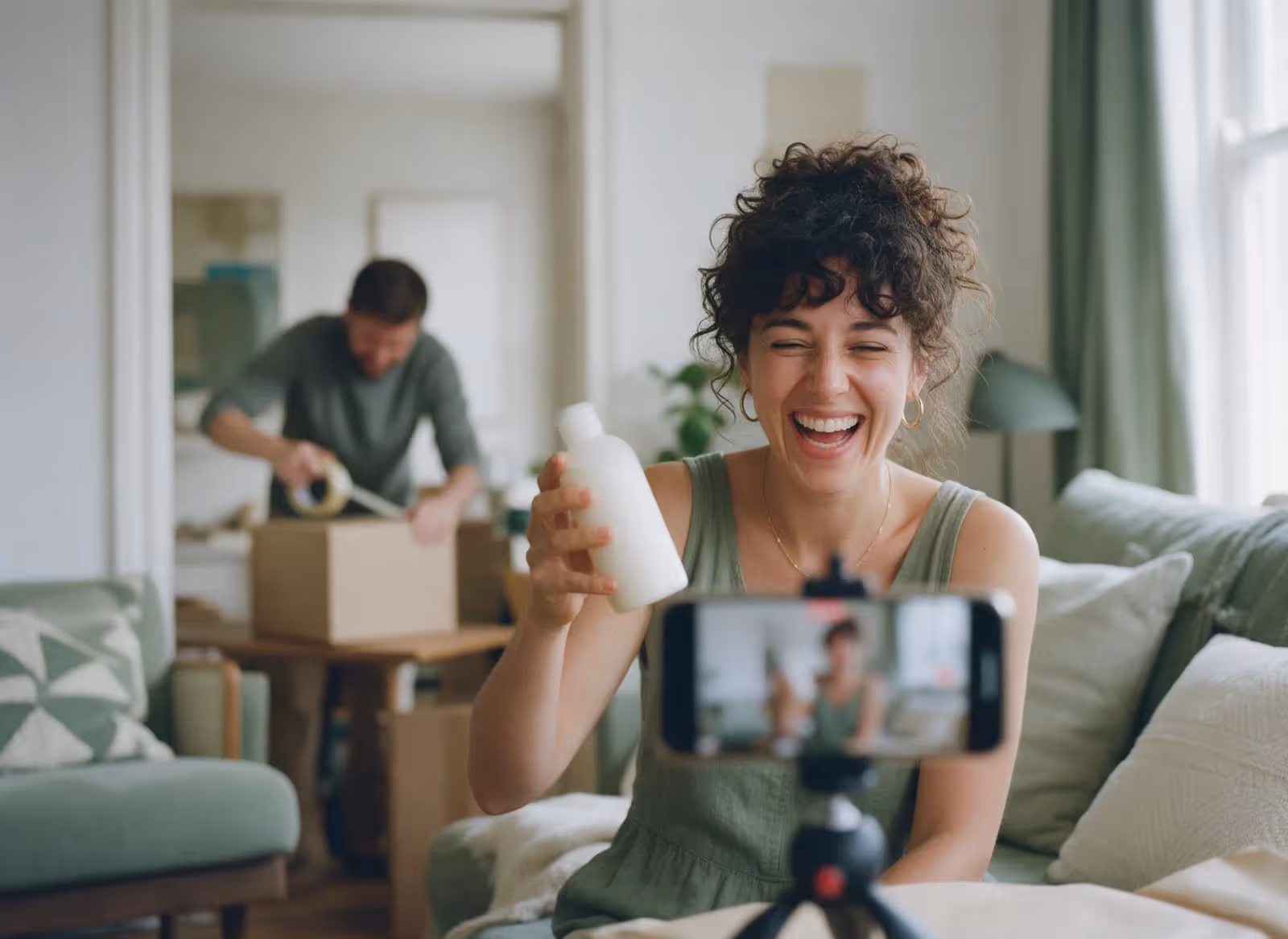 A creator filming with a phone while a parcel is packed behind her